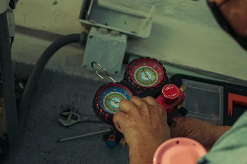 Technician reading refrigerant pressure gauges