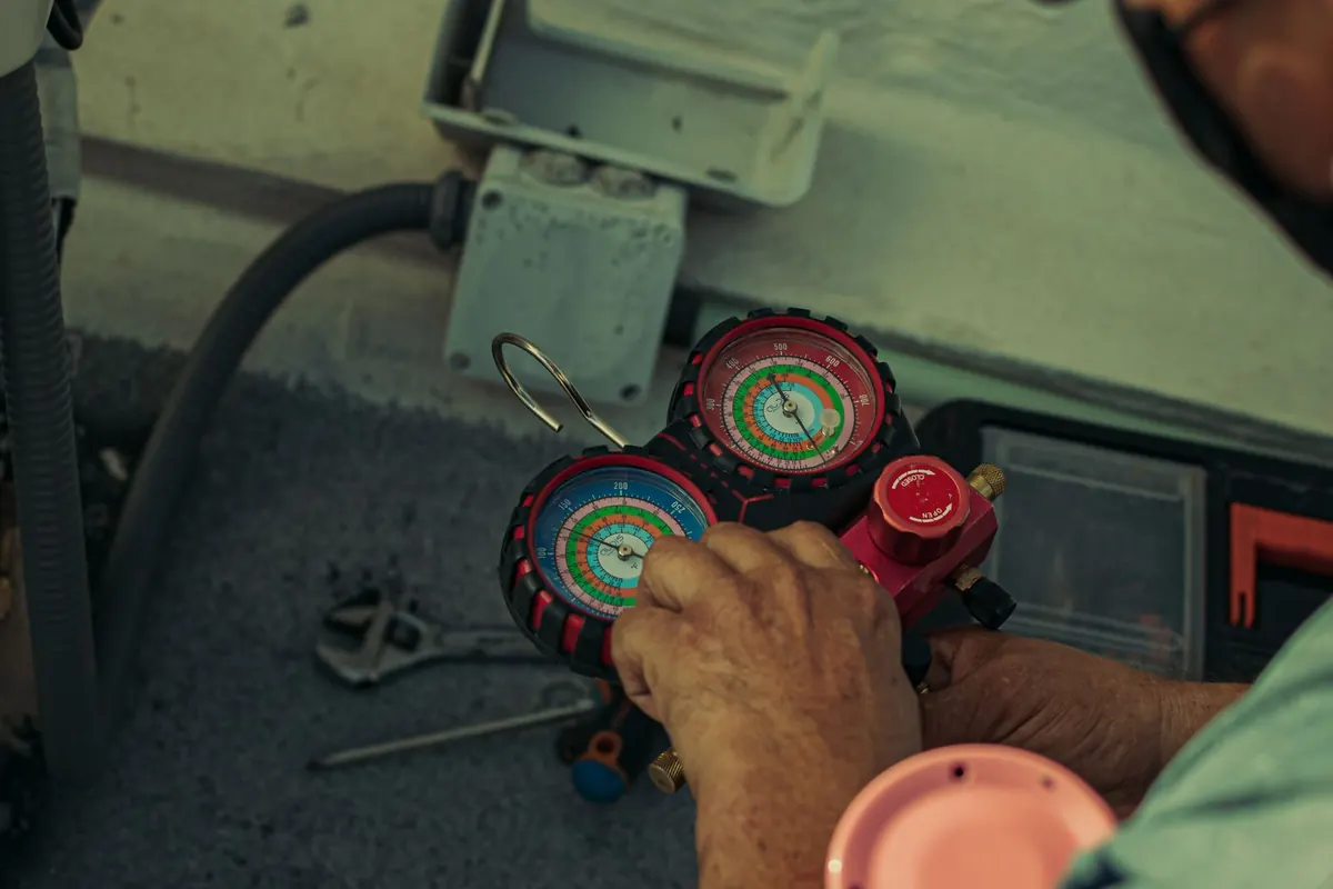 Technician reading refrigerant pressure gauges