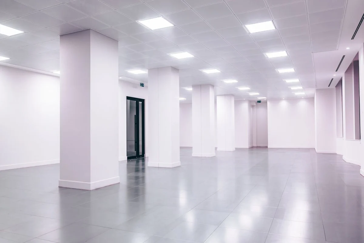 Empty white office space with columns and ceiling lights