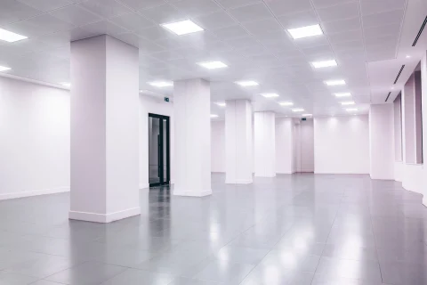 Empty white office space with columns and ceiling lights