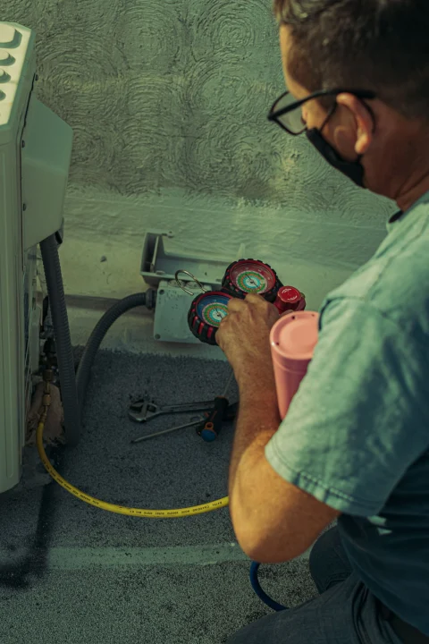 HVAC technician checking an outdoor unit with gauges