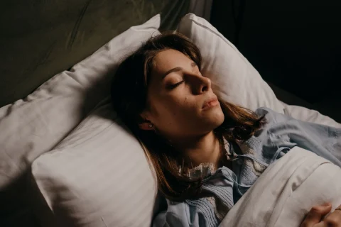 Woman sleeping on a white pillow in a dark bedroom