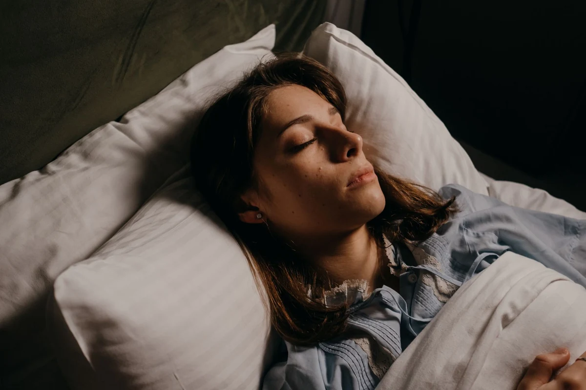 Woman sleeping on a white pillow in a dark bedroom