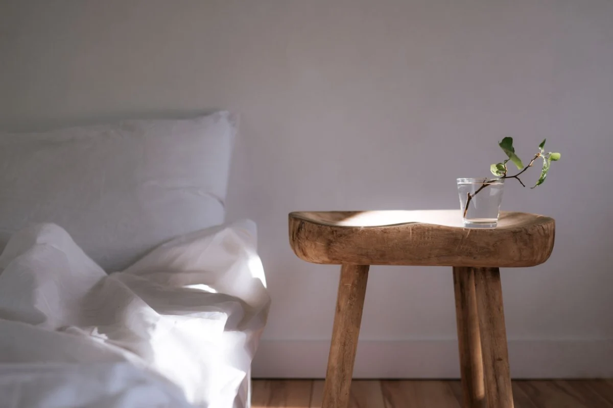 Minimal bedroom with white linens and a wooden side table