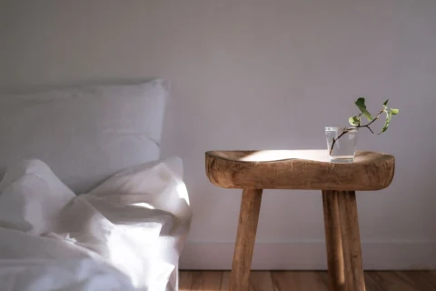 Minimal bedroom with white linens and a wooden side table